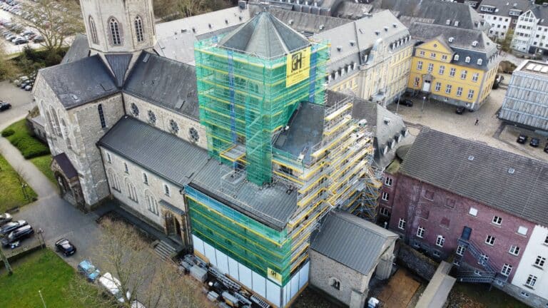 Eine  Kirche  wird  renoviert  und  ist  mit  grünem  Baugerüst  und  gelbem  Netz  umhüllt